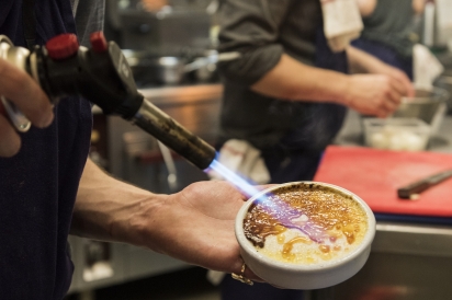 Caramelizing the top of a crême brulée in the kitchen at Au Passage in Paris.