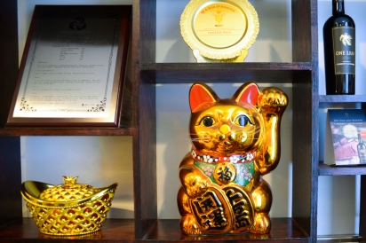 A lucky cat is displayed alongside awards at Szechuan House in Flushing.
