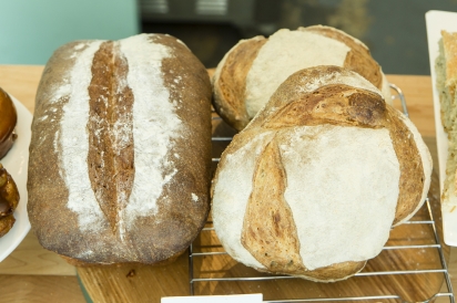 A loaf of wheat bread alongside two sourdough boules at Rockaway Beach Bakery, Queens, New York.