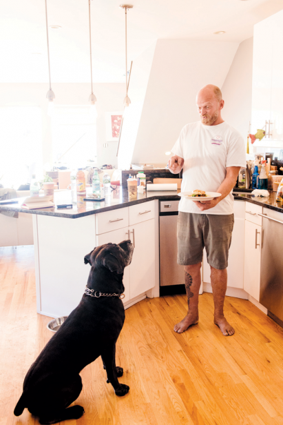 Chef Whitney Aycock at home in Queens with his dog, Renzo, amidst his eclectic collections.